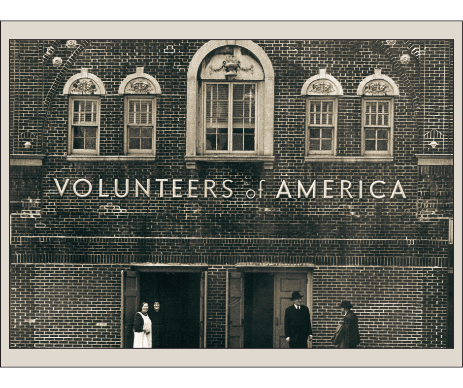 Vintage black and white photo of a Volunteers of America building with three people standing outside